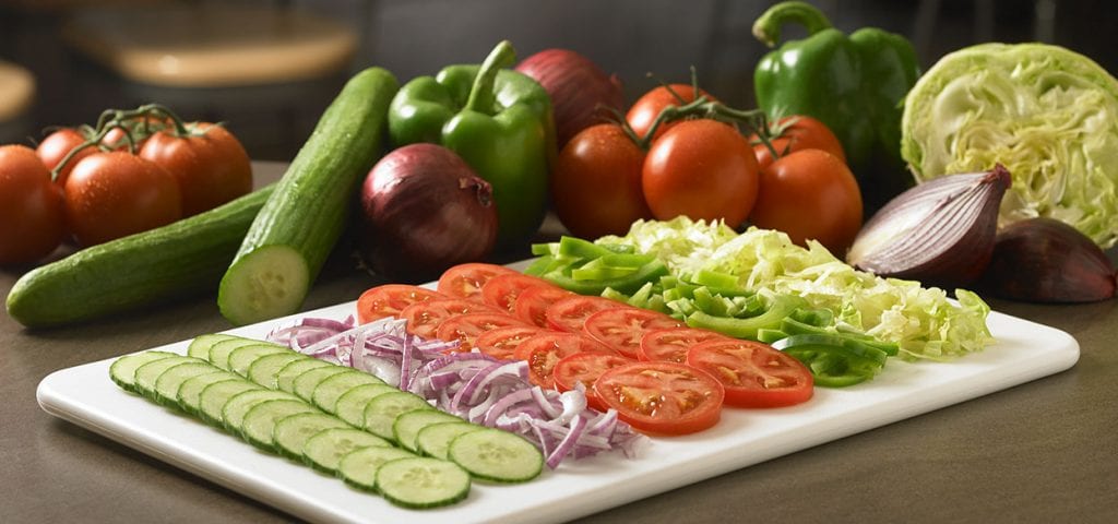 Mr.Sub cutting board with neatly arranged cut cucumber tomatoes red onion green peppers lettuce